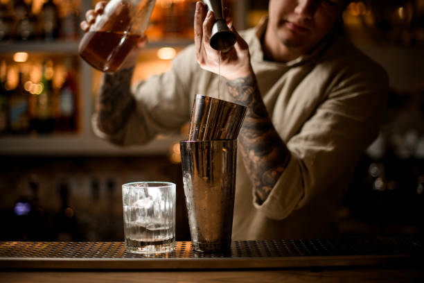 istock barman gently pours drink from metal jigger into shaker on bar counter 1289703657
