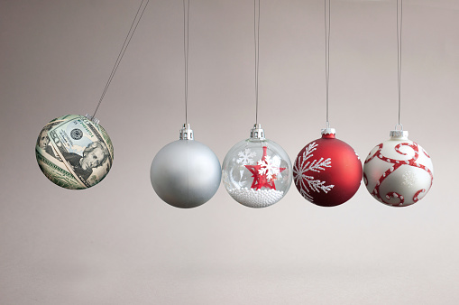 Dollar bauble colliding into christmas ornaments, seasonal shopping budget and balancing finances concept