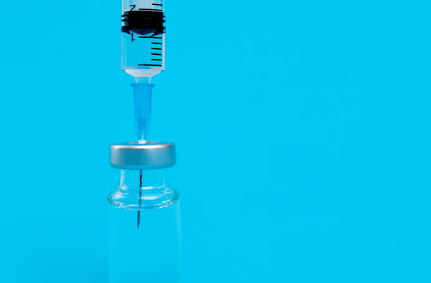 istock Syringe inserted into the vial on blue background 1289704720