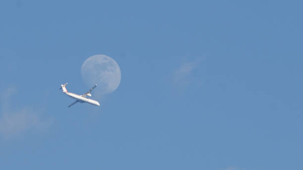 istock The half moon in the morning with a plane passing through the sky 1289704769