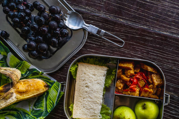 repas végétalien sain dans la vaisselle de cuisine écologique : récipient en métal inoxydable ou boîte à lunch, enveloppements de cire d’abeille avec spork sur fond en bois. zéro déchet et mode de vie durable sans plastique - lunch box lunch box metal photos et images de collection