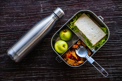Stainless steel container or lunch box with healthy vegetarian meal and reusable thermo bottle on wooden background. Eco-friendly kitchen products. Zero waste and sustainable plastic free lifestyle
