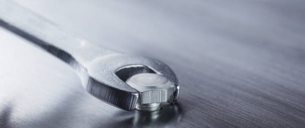 istock Wrench tightens bolt in steel billet. Spanner, bolt, screw and nuts. 1289706196