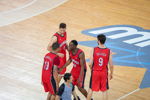 Basketball players in red jersey celebrating their victory in court.