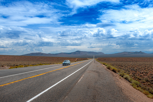 Nevada, USA - August 3, 2014: A vintage car traveling along the  US route 50 (known as the Loneliest Road in America) in the State of Nevada, USA.