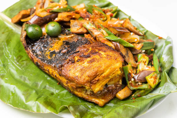 バナナの葉に盛り付けられたスパイスと野菜の人気グリルスティングレイフィッシュのクローズアップ - prepared fish fish grilled close up ストックフォトと画像