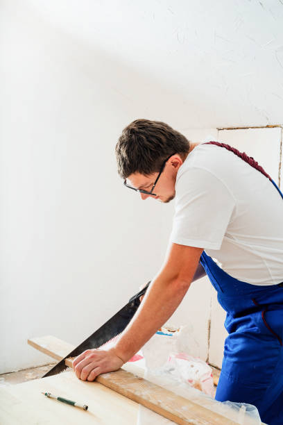 istock carpenter in blue overalls sawing a board with a hand saw 1289709767