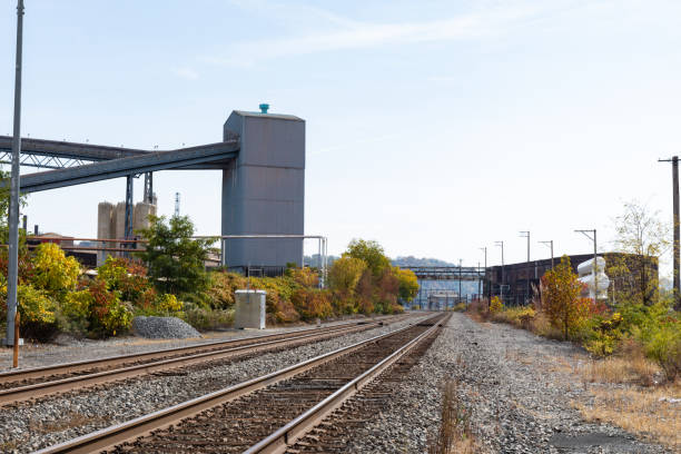 istock Train tracks running alongside a steel mill industrial complex, fall season with blue and cloudy skies 1289709903