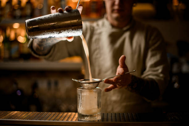 istock bartender holds sieve over old fashioned glass and pours cocktail from shaker. 1289710744