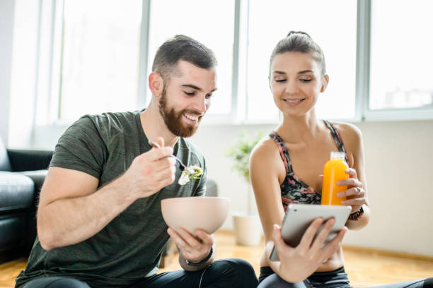 istock Happy couple using digital tablet and eating snack after intensive home workout 1289712430