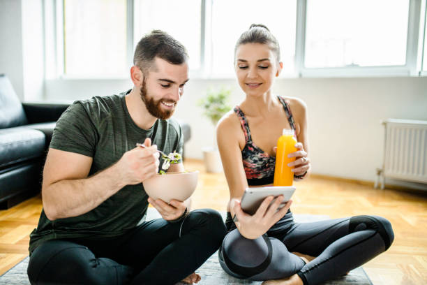 istock Happy couple using digital tablet and eating snack after intensive home workout 1289712523