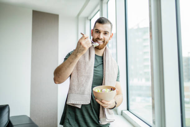 istock Young man eating fresh salad after intensive home workout 1289713533