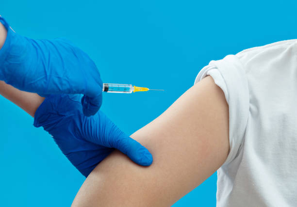 istock Doctor vaccinating for a boy on blue background 1289716524