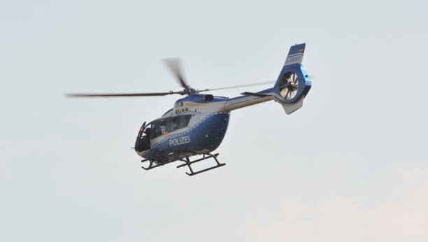 um helicóptero da polícia sobrevoa a cidade em busca de um criminoso. o policial abriu a porta do helicóptero no ar para dar uma olhada mais de perto no que estava no chão. - police helicopter - fotografias e filmes do acervo