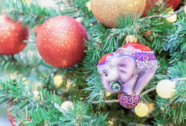 Photo of Glass Christmas tree toy in the form of a circus elephant on a violet ball.