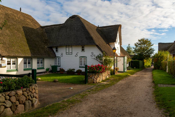 Amrum, Germany - October 17, 2020: Small path with thatched houses at a sunny autumn day