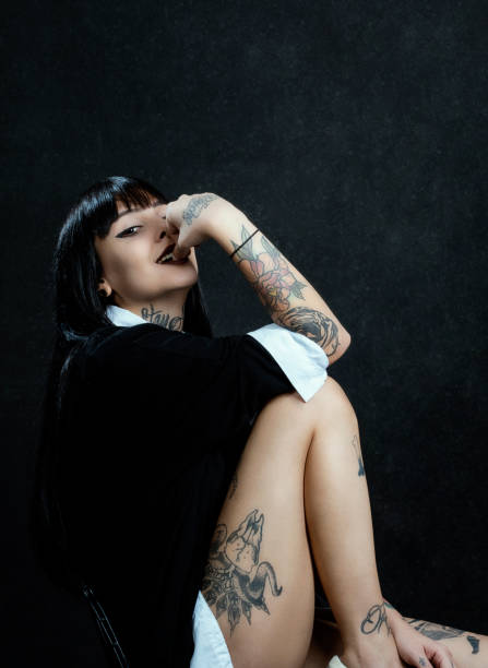istock Tattooed young female posing in studio over black background 1289719571