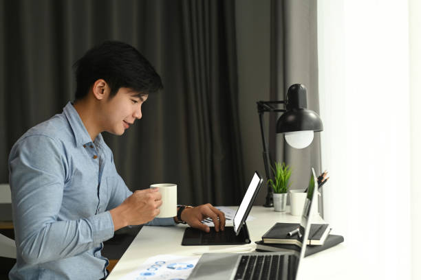 istock Side view of a graphic designer is working with computer tablet and drinking coffee at his workspace in the morning. 1289719660