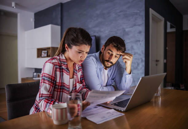 istock Nervous young couple sitting at home, paying bills online. 1289722054