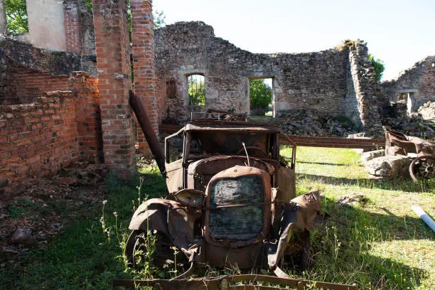 Ruin of the village of Oradour sur Glane in France with a rusty old car, remnant of an old war massacre