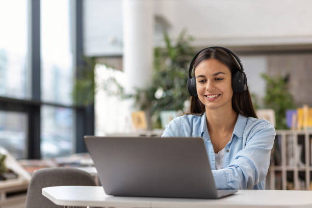 istock Young woman talk on video call at the table using headphones Remote work or learning concept 1289723155
