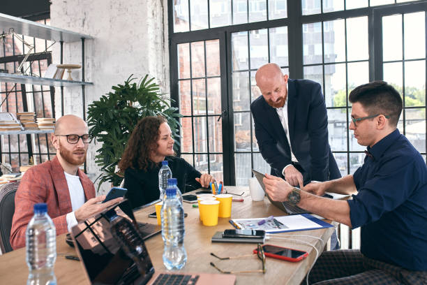 istock Beautiful business people are using gadgets, talking and smiling during the conference in office 1289726049