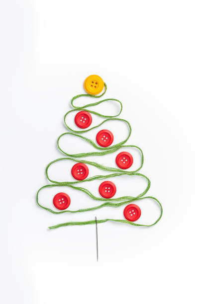 Sewing theme creative flat lay design: Christmas tree made of needle, thread and buttons.