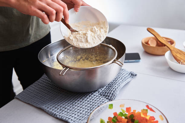 istock Woman in kitchen cooking a dough. Hands pour flour into a bowl 1289728981