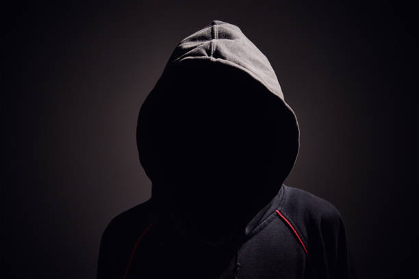 istock Silhouette af man without face in hood on black background. Anonymous crime concept 1289729021