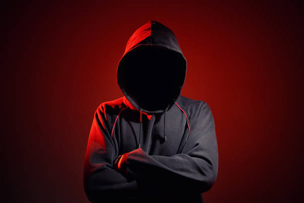 silhouette af uomo senza volto in cappuccio su sfondo rosso. concetto di crimine anonimo - uomo incappucciato foto e immagini stock