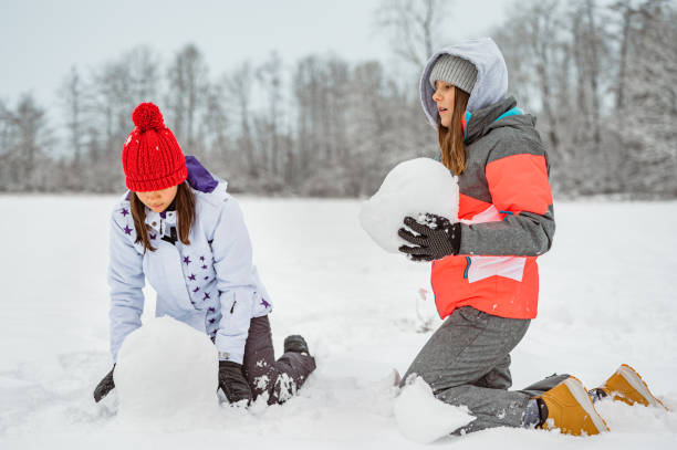 istock Two girls making a snowman in a winter time 1289733285