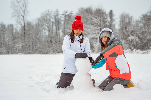 istock Two girls making a snowman in a winter time 1289733544