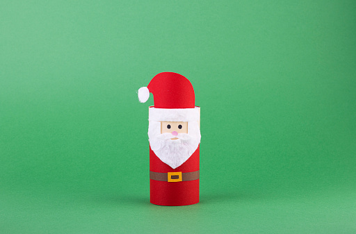 paper Christmas crafts for children on a green background. toilet paper Santa Claus