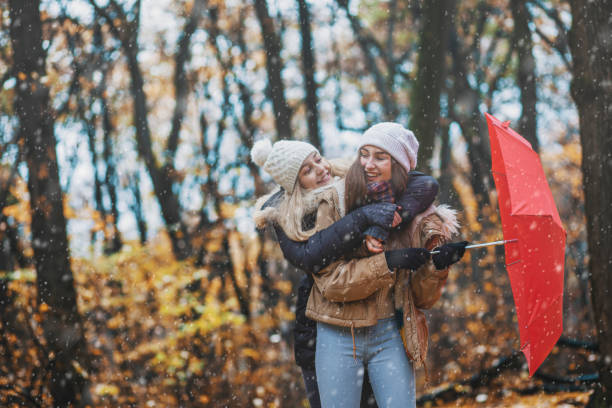 istock Beautiful young women enjoying together while snowing in forest 1289737066