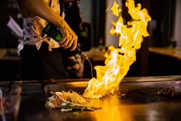 teppan show at a traditional Japanese restaurant. hands of the cook. Japanese cook prepares meat, fish, rice, vegetables for guests