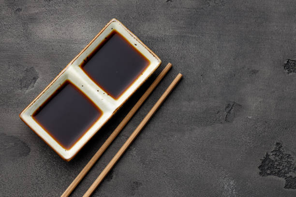 istock Bowl with soy sauce for sushi and chopsticks on black background 1289738728