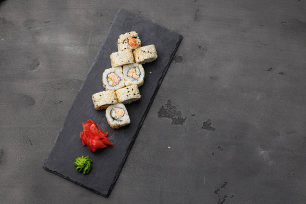 istock Top view of sushi roll with sesame on dark grey background 1289739868