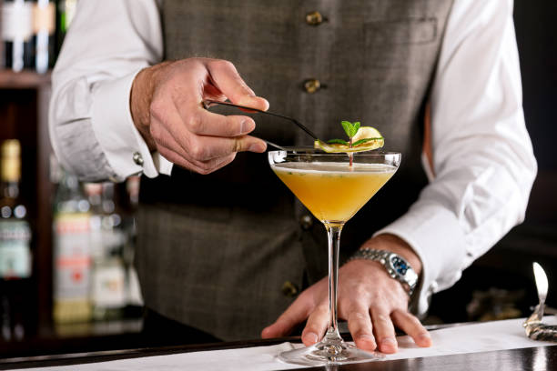 istock Bartender decorating alcohol cocktail with a slice of lemon and mint leaf 1289740142
