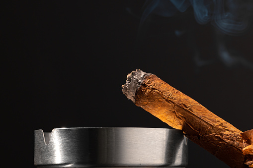 hands with lighter and cigar isolated on black
