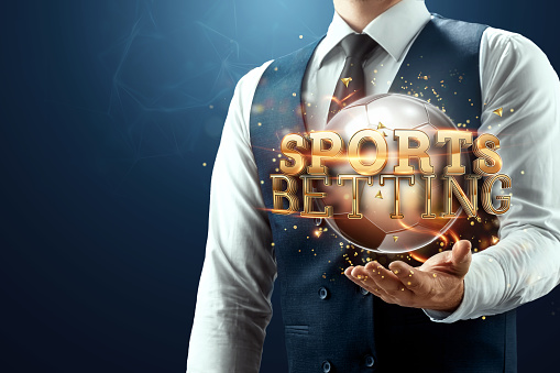 The businessman has a gold inscription sports betting on his palm. Concept for gambling, sports, online betting. Mixed environment.