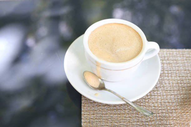 A cup of coffee on a saucer with a careless drip on the table. Coffee with foam on the nature.