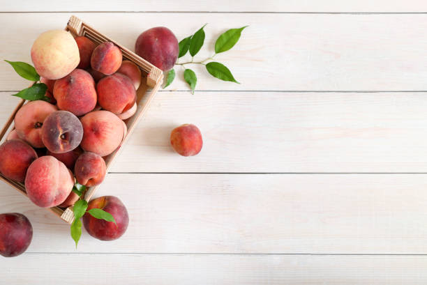 istock Ripe peaches in a box on wooden background top view 1289749032