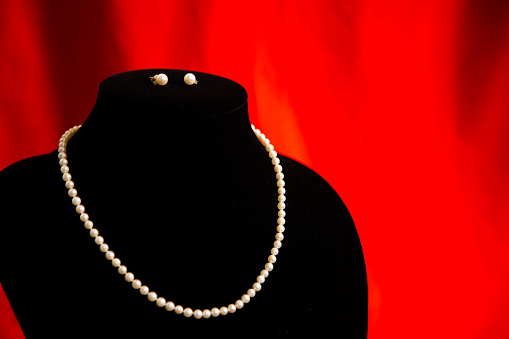 Elegant white pearl necklace and earrings on black background