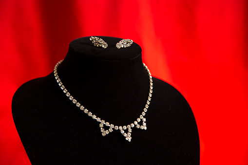 Gold ruby diamond teardrop necklace on a black jewelry bust. 3d illustration
