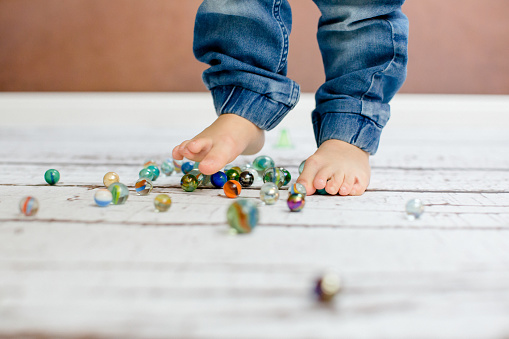 Boy playing with glas marbles on the floor.
