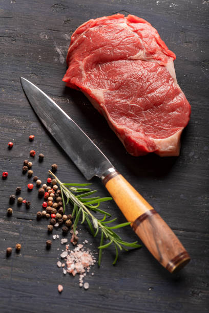 istock Beef filet with knife salt pepper and rosemary on black background 1289754236