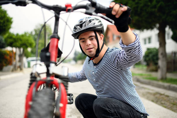 Portrait of down syndrome adult man with bicycle standing outdoors on street. Portrait of down syndrome adult man with bicycle and helmet standing outdoors on street. down syndrome photos stock pictures, royalty-free photos & images