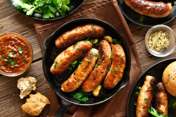 Roasted sausages in frying pan Tasty fried sausages in frying pan over wooden background. Top view, flat lay sausage stock pictures, royalty-free photos & images
