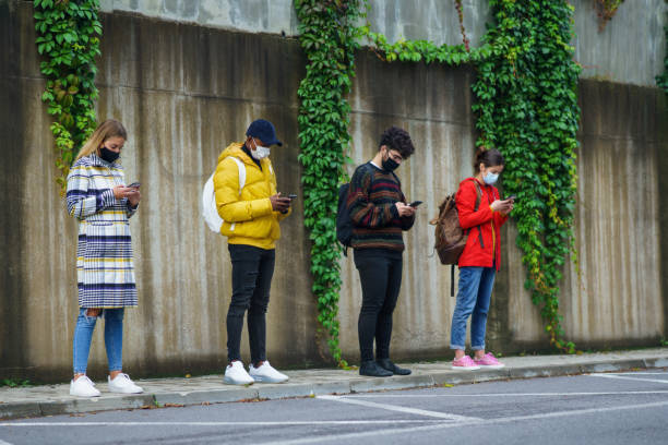 istock Young people using smartphone outdoors in town. Coronavirus and safe distance concept. 1289759982