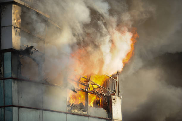 Fire and smoke engulfs a metal and glass office building with the sunset light coming from a side. Fire and smoke engulfs a metal and glass office building with the sunset light coming from a side. inferno stock pictures, royalty-free photos & images